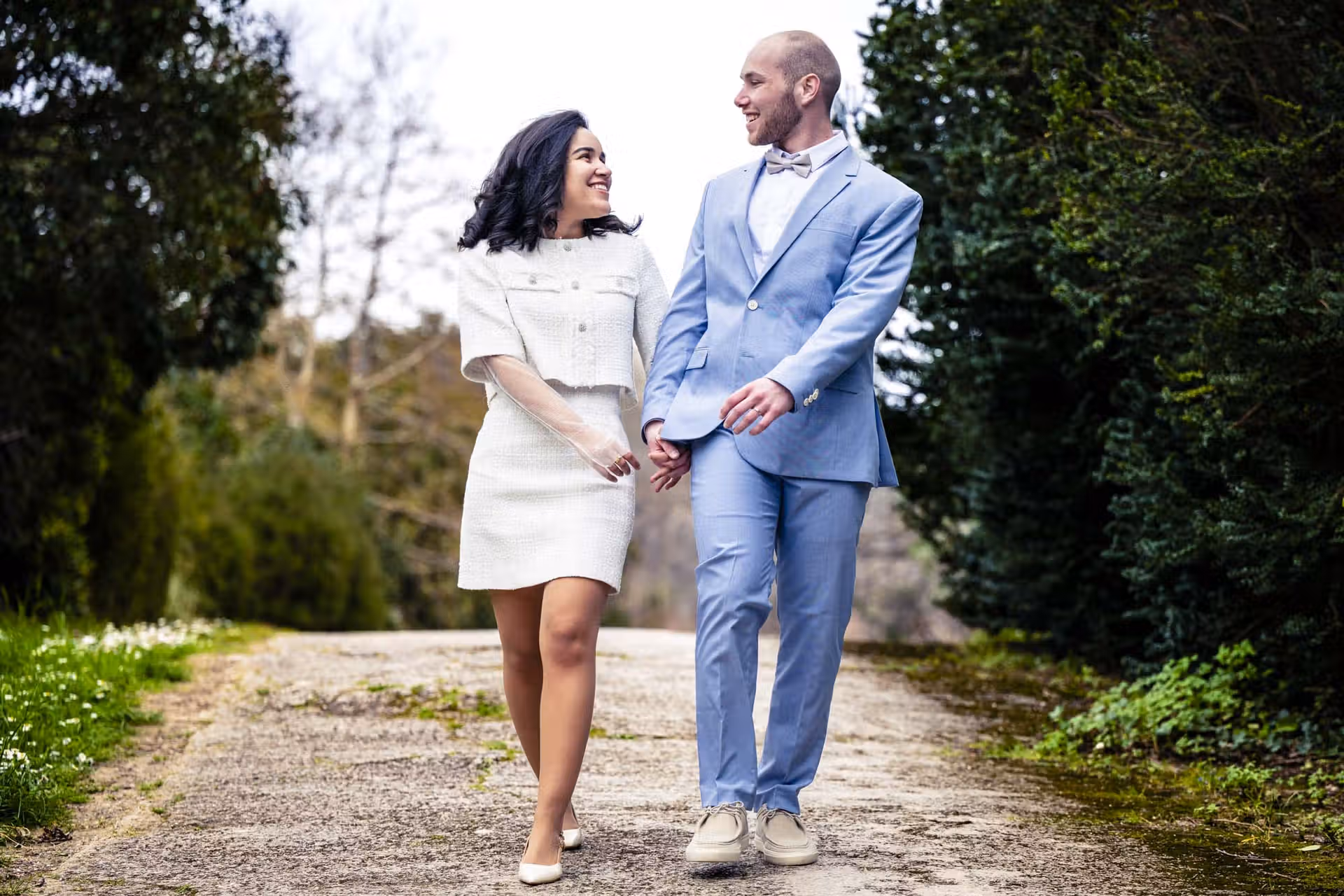 Couple de mariés marchant main dans la main en se regardant avec complicité dans un parc à Marseille - Photographe Mariage Provence.