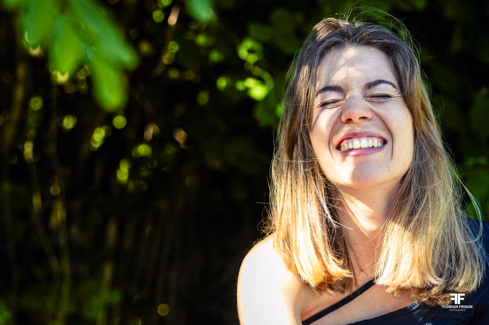 Portrait spontané d'une femme riant aux éclats lors d'une séance photo lumière naturelle à Aix-les-Bains, près du lac du Bourget.